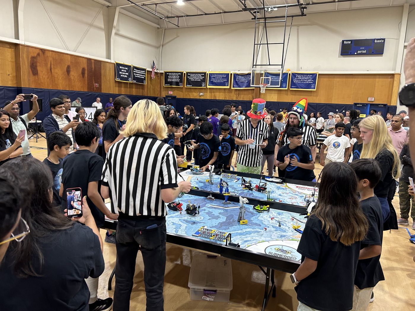 Referees and students surround their tables and robots- the game is on!